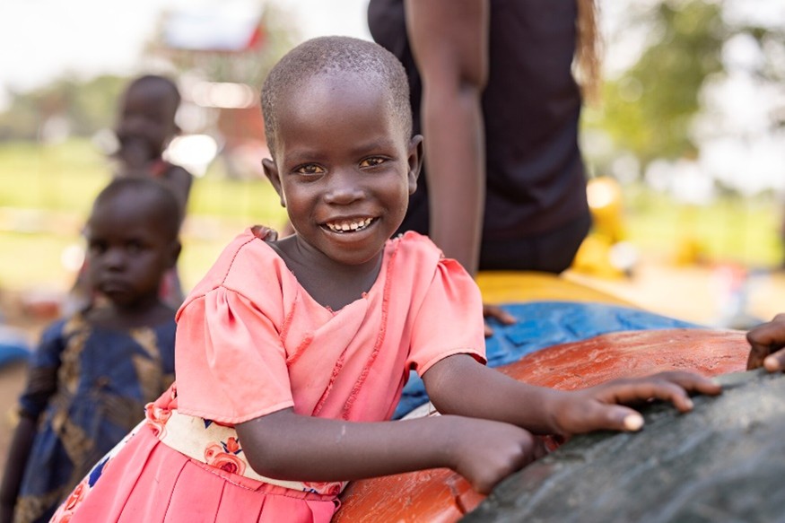 A girl in a pink dress smiles.