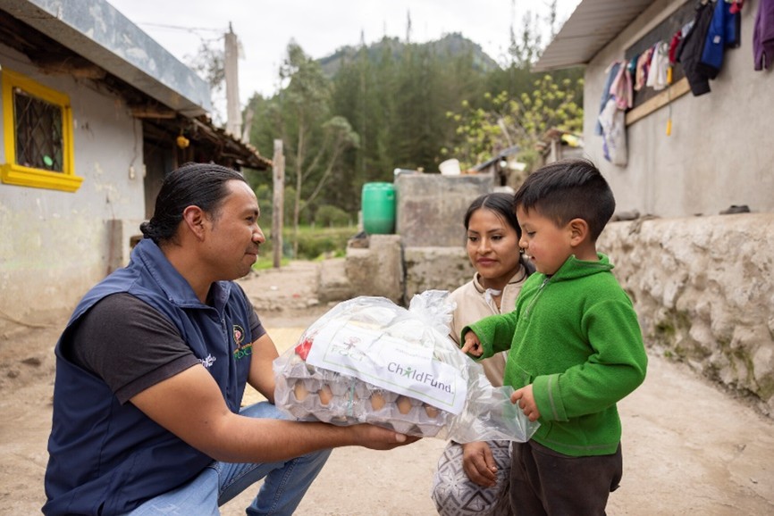 Aid worker hands out eggs to a mother and child