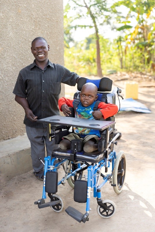 Six-year-old Robert and his dad celebrate the gift of a wheelchair they received from ChildFund’s local partner, Partners for Children Worldwide.