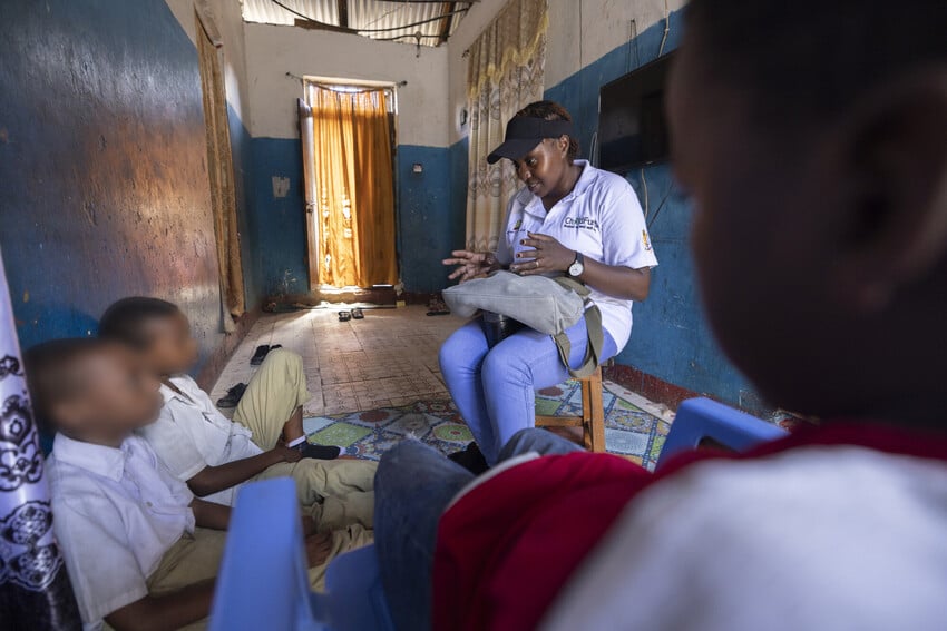 Psychologist speaks to a group of children in a home in Kenya. Children's faces are blurred.